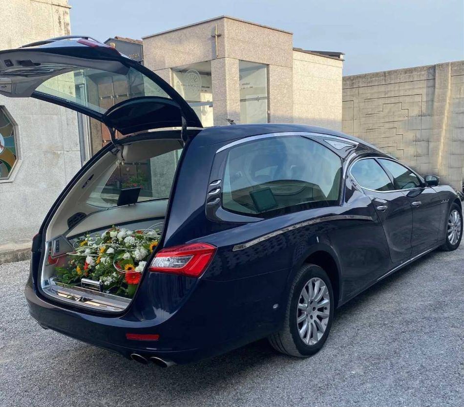 Un carro funebre dell’impresa con il portellone aperto e i fiori per la cerimonia